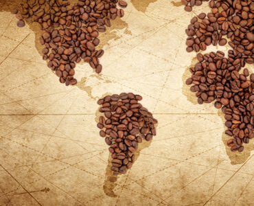 Grãos de café em cima de um mapa mundi