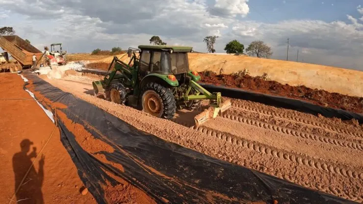 Trator fazendo o processo de ensilagem de grão reidratado de sorgo.