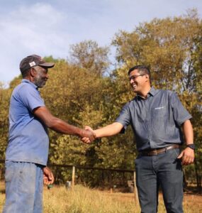 Dois homens se cumprimentando em uma fazenda