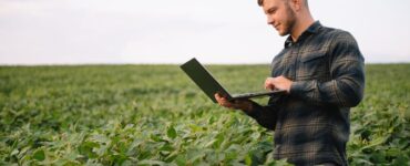 Homem no meio de uma lavoura de soja com um notebook