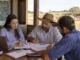 Três pessoas analisando documentos em uma fazenda